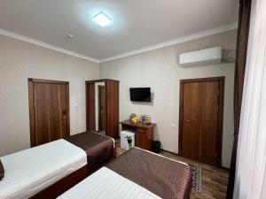 a hotel room with two beds and a television at Al-Khabib in Bukhara