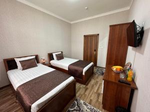 a hotel room with two beds and a television at Al-Khabib in Bukhara