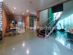 a living room with a staircase and a dining room at Nillo Hotel Kebumen Mitra RedDoorz in Kebumen