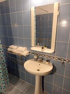 a blue tiled bathroom with a sink and a mirror at SuiteMateo in Cluj-Napoca