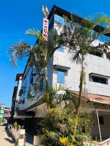 un edificio con palmeras delante en Coorg HillTown Hotel - Madikeri en Madikeri