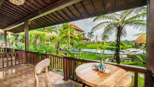 una terraza de madera con mesa, sillas y piscina en Umakelod Sebatu Villas, en Ubud