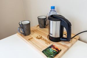 a tea kettle and two cups on a cutting board at AYKUN Hotel in Almaty