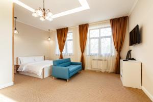 um quarto com uma cama e uma cadeira azul em AYKUN Hotel em Almaty