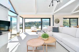 a living room with a white couch and a table at Akaroa Harbour View - Christchurch Holiday Homes in Akaroa