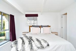 Un dormitorio blanco con una cama con una manta. en Akaroa Harbour View - Christchurch Holiday Homes, en Akaroa