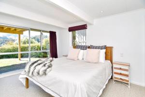 una camera da letto con un letto bianco e una grande finestra di Akaroa Harbour View - Christchurch Holiday Homes ad Akaroa