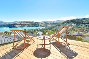 2 sillas y una mesa en una terraza con vistas en Akaroa Harbour View - Christchurch Holiday Homes, en Akaroa