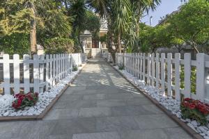 a white picket fence with flowers and a walkway at Villa Imperamare in Santa Maria di Castellabate
