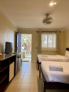 a hotel room with two beds and a television at Panglao Regents Park Resort in Panglao Island