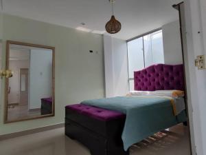 1 dormitorio con cama morada y espejo en Casa Piscina Duna Saraja Ica-Perú en Ica