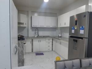 uma cozinha com armários brancos e um frigorífico em Casa Piscina Duna Saraja Ica-Perú em Ica