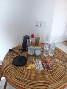 a round wooden table with a coffee maker and drinks at El Ling guesthouse in Kep