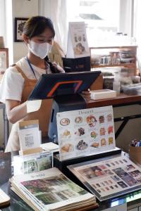 a woman wearing a face mask behind a counter in a store at Delio Boutique Hotel in Udon Thani