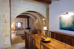 una sala da pranzo con tavolo e parete in pietra di OneFifty Gozitan Villa and Pool - Happy Rentals a Il-Pergla