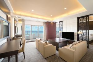 a living room with a table and chairs and a television at Grand Mercure Okinawa Cape Zanpa Resort in Yomitan