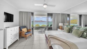 a bedroom with a large bed and a view of the ocean at Lagoon Beachfront Lodge 202 on Hamilton Island by HamoRent in Hamilton Island
