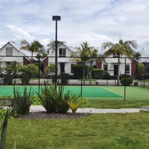 einen Tennisplatz mit einem grünen Tennisplatz in der Unterkunft Kuirau Chalet Villa 3-bedroom Twin Lake in Rotorua