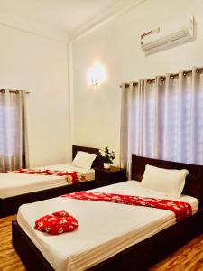 1 Schlafzimmer mit 2 Betten und roter Bettwäsche in der Unterkunft Aspire Homestay in Siem Reap