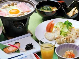 a table with two plates of food and a drink at Kidoike Onsen Hotel in Yamanouchi