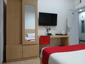 Schlafzimmer mit einem Bett, einem TV und einem Spiegel in der Unterkunft Macan Kumbang Residence in Palembang