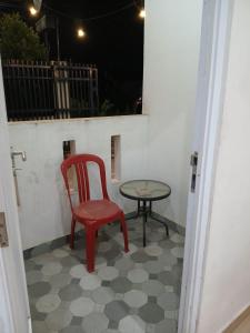 einen roten Stuhl und einen Tisch auf der Terrasse in der Unterkunft Macan Kumbang Residence in Palembang
