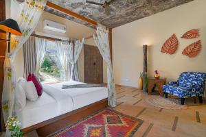 a bedroom with a bed and a window and a chair at SaffronStays Moringa Wishing Tree in Udaipur