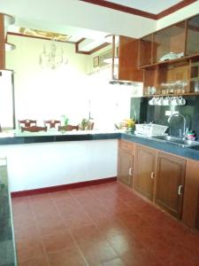 cocina con armarios de madera y suelo de baldosa en Villa Ceferina en Tagbilaran City