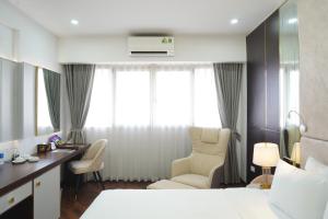 a hotel room with a bed and a desk and chairs at Bao Son International Hotel in Hanoi