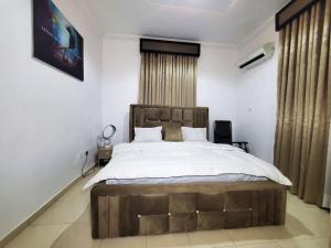 um quarto com uma cama grande e uma cabeceira em madeira em 3 bedrooms with Modern Amenities em Abeokuta