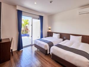 Habitación de hotel con 2 camas y puerta corredera de cristal en The Pool & Sauna Villa MOTOBU, en Motobu