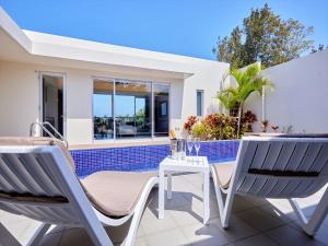 - une terrasse avec 2 chaises et une table à côté de la piscine dans l'établissement The Pool & Sauna Villa MOTOBU, à Motobu