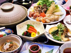 una mesa con muchos platos de comida. en Kidoike Onsen Hotel, en Yamanouchi