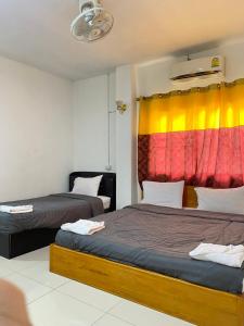 a bedroom with two beds and a colorful curtain at Hom pho guesthouse in Ban Houayxay