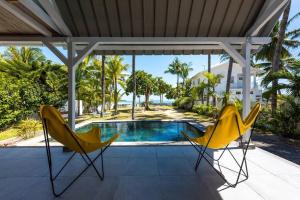 - deux chaises jaunes assises sur une terrasse couverte à côté d'une piscine dans l'établissement Quaint Beach Villa in a fishing village, à Grand Gaube
