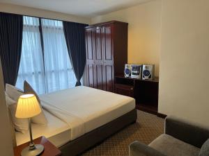 a bedroom with a bed with a lamp and a chair at Serviced Apartments @ Times Square Kuala Lumpur in Kuala Lumpur