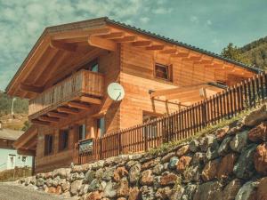 Cette maison en bois dispose d'un balcon et d'une horloge. dans l'établissement Saerbeck mountain hut, à Heiligenblut