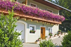 una casa con flores púrpuras en un balcón en Apartment Adlerhorst - Schwalbenhof Farm, 