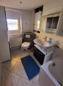 een badkamer met een wastafel, een toilet en een wastafel bij NEU! Ferienwohnung Sommeralmblick in Schiffweiler