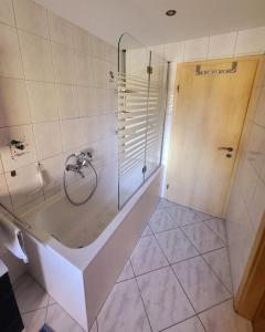 een badkamer met een bad en een glazen douche bij NEU! Ferienwohnung Sommeralmblick in Schiffweiler