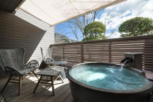 a hot tub on a deck with chairs and a table at nol hakone myojindai in Hakone