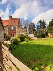 a house with a fence in front of a yard at Gîte de la Ferme du Clos Giot in Saint-Vaast-la-Hougue