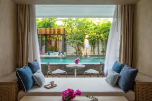 een woonkamer met een bank, een tafel en een zwembad bij Cape Nidhra Hotel in Hua Hin