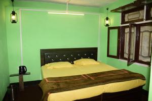 een slaapkamer met een groot bed met groene muren bij NotOnMap- Hidden Hamlet Gowari in Tisa