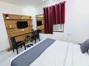 a bedroom with a bed and a desk and a television at Hotel TU Casa (Stay near International Airport) in New Delhi