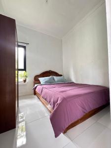 um quarto com uma cama com um cobertor roxo em Abimanyu Guesthouse em Sumedang