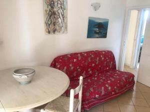 un soggiorno con divano rosso e tavolo di Holiday apartment in Porto Pollo a Porto Pollo