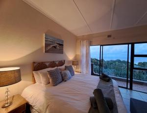 a bedroom with a large bed and a large window at 8 Eden Palms, Palm Beach in Port Edward