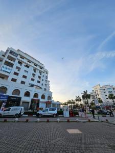 ein großes weißes Gebäude mit davor geparkt in der Unterkunft la perle du tanger R in Tangier