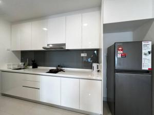 a kitchen with white cabinets and a refrigerator at Bora Residences by Antlerzone in Johor Bahru